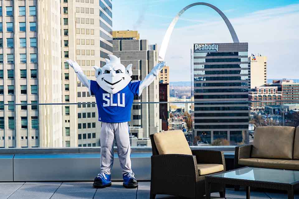SLU Billiken in downtown St Louis SLU Billiken mascot standing on a rooftop near the Arch