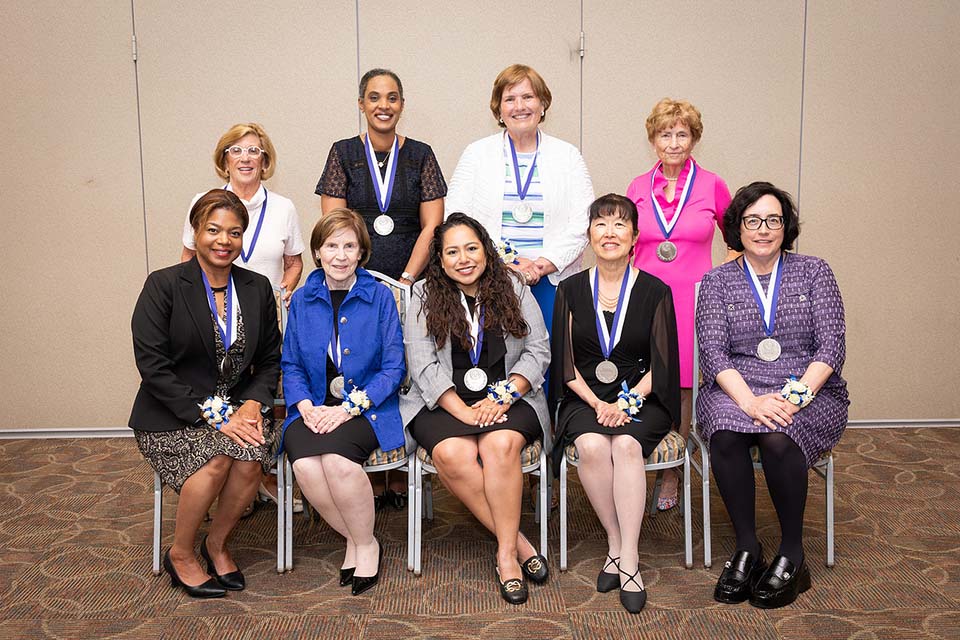 A group of nine alumni merit awardees pose for a photo together.