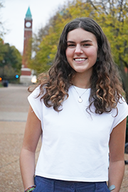 Anna Godlewski A headshot photo of Anna Godlewski with a clocktower and trees in the background.