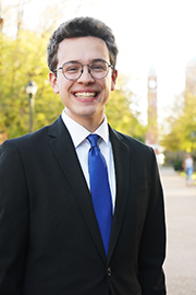 Michael Poirier A headshot photo of Michael Poirier with a clocktower and trees in the background.
