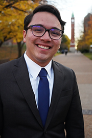 Nate Reyes A headshot photo of Nate Reyes with a clocktower and trees in the background.