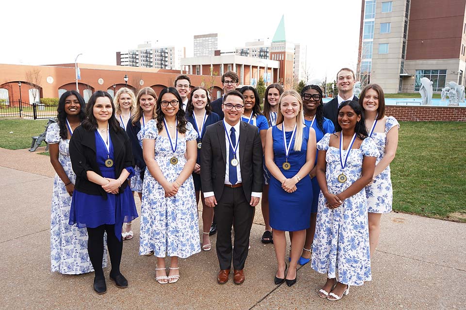 Spirit of the Billiken A large group of students dressed nicely and with medals around their neck pose for a photo outside on SLU's campus.