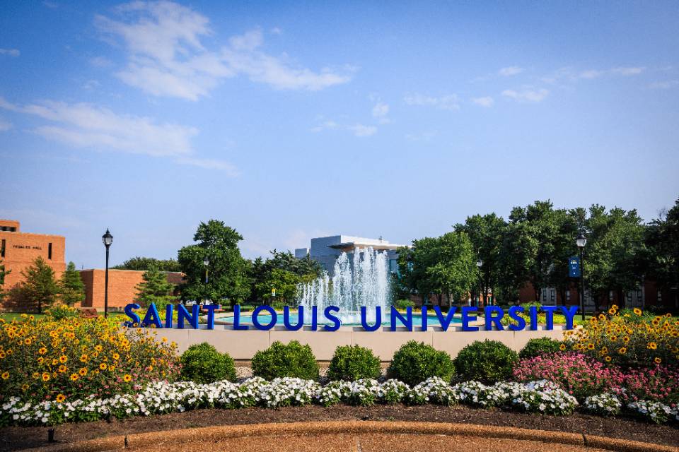 SLU Photo of a fountain Scene of SLU fountain with flowers with Saint Louis University spelled out in large letters and displayed on the edge of the fountain