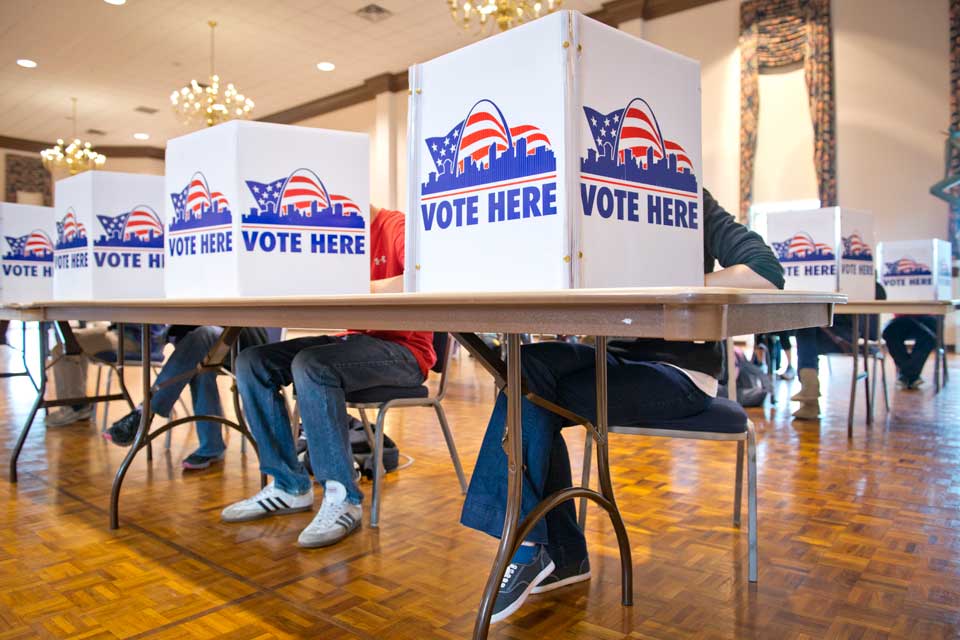 Students voting in Busch Student Center Students vote behind small barriers that read Vote Here at tables in the Saint Louis Room.
