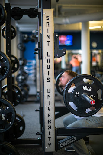 Student Lifting A man squats while lifting weights, with a bar bell over his shoulders.