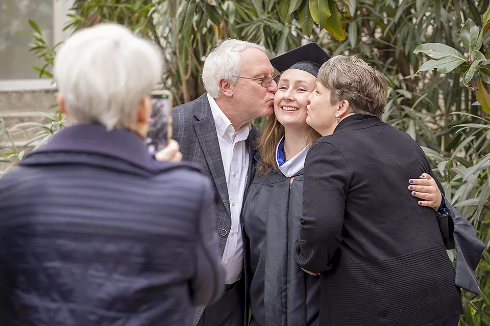 SLU Madrid Ceremony A woman hugs a participant in a graduation ceremony and looks up at the sky, while others mill around the area.