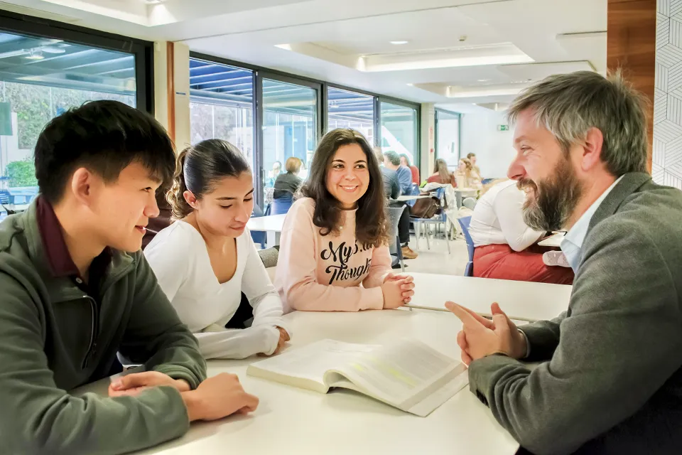 Creative Writing Summer Institute A professor is talking to three students in an area of the cafeteria.