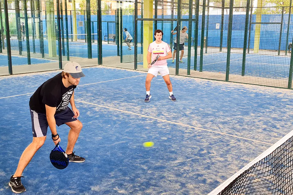 SLU-Madrid Athletics Three students play soccer on a field outside.