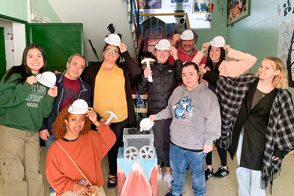 Students and a professor pose with cardboard cut outs of construction helmets and hammers.