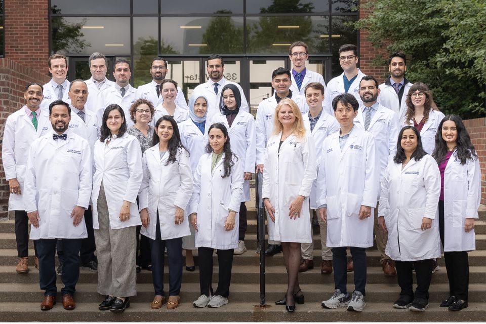The group of 2025 neurology residents stand on stairs in front of a building for a group pic.