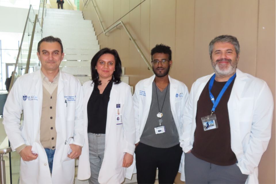 The PET/CT fellow and nuclear medicine residents in a group shot taken at the bottom of a long staircase.