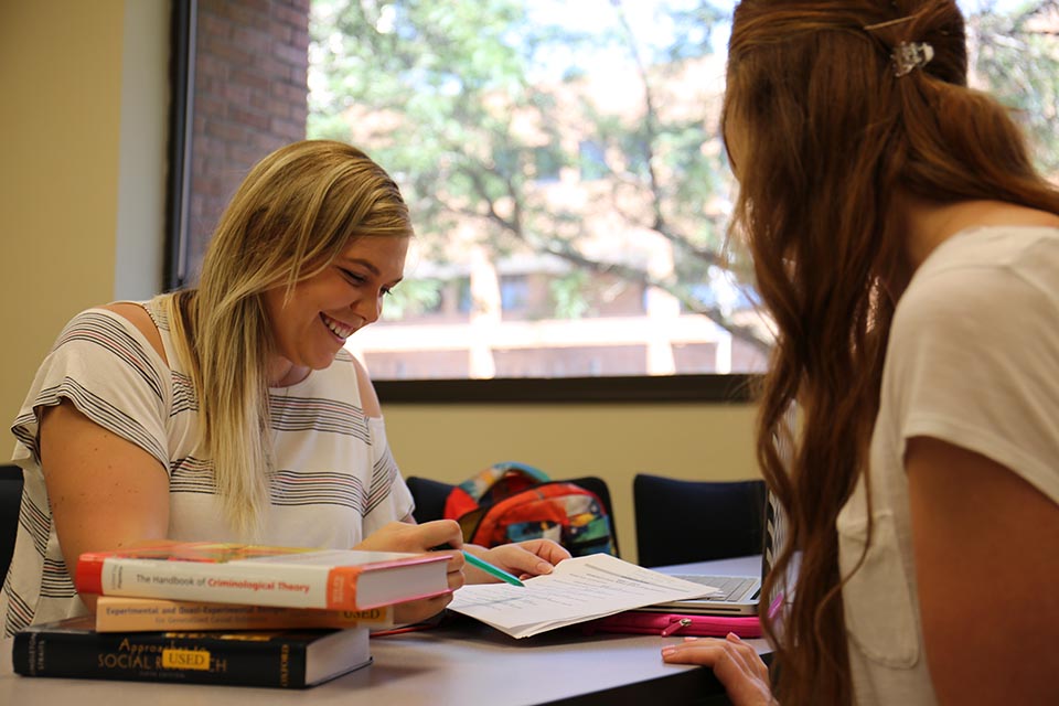 Two female students sitting in a classroom studying.