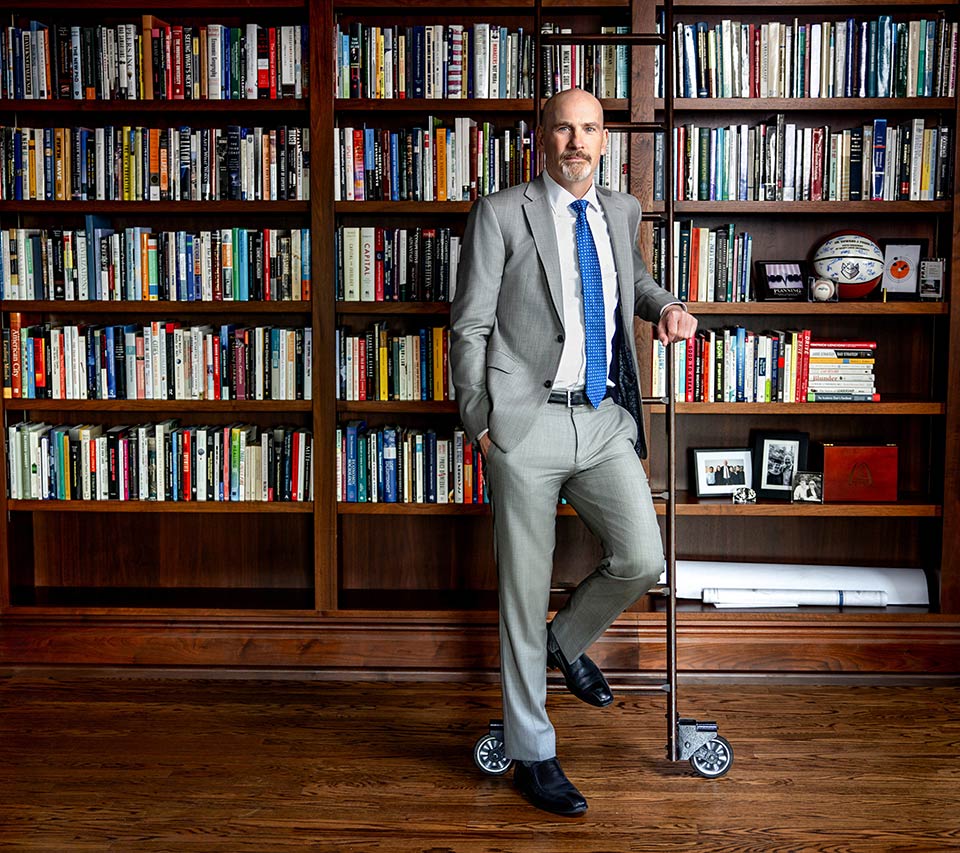 SLU President Dr. Ed Feser poses in front of a wall of bookcases in his office.